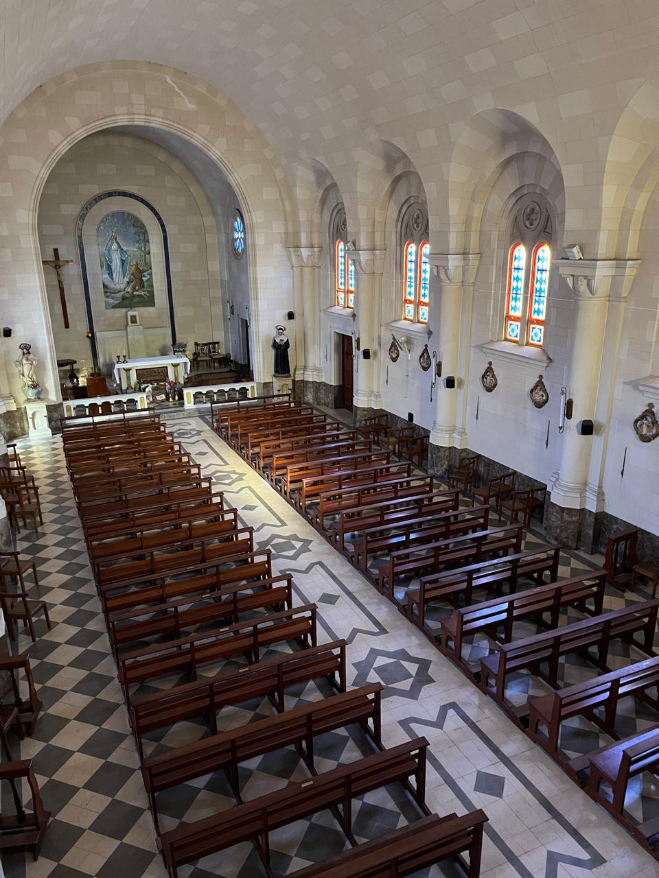 Interior de la capilla: nave con bancos, vitrales y altar